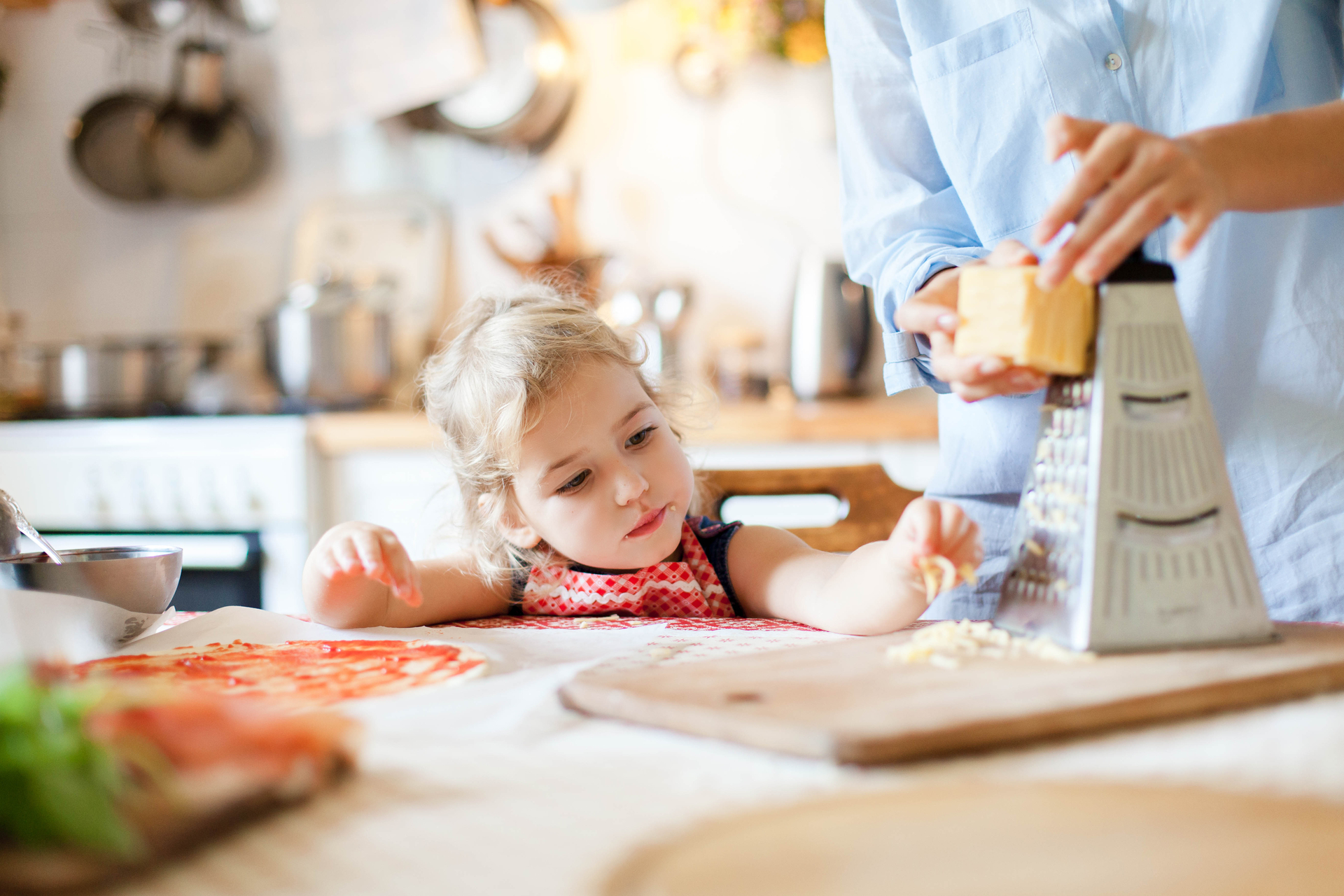 Little girl eating Parmigiano Reggiano in the kitchen